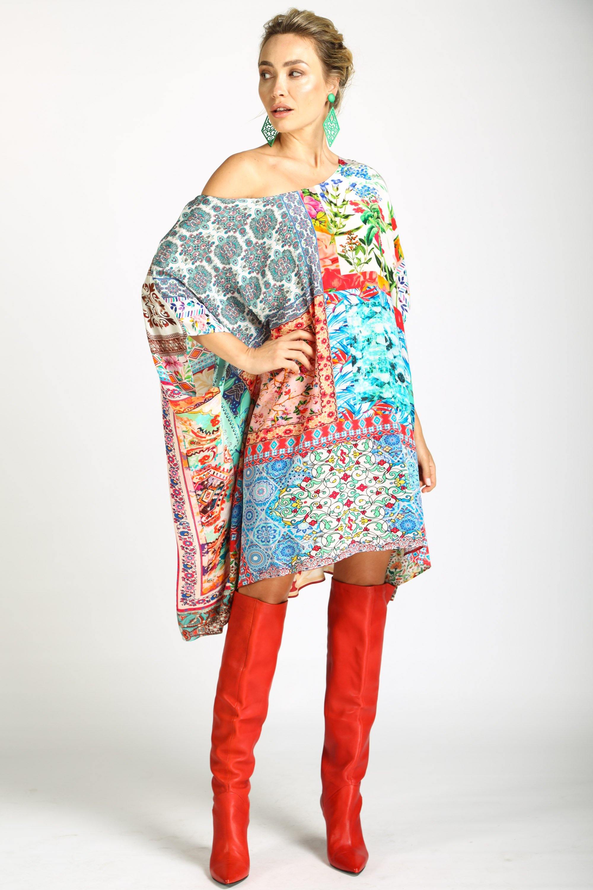 Side View of the Bohemian-style Short Box Kaftan, Damascus print. The kaftan dress is worn with red knee-high boots, highlighting the asymmetrical, flowing hemline and the vibrant mix of blue, red, pink, and white prints.
