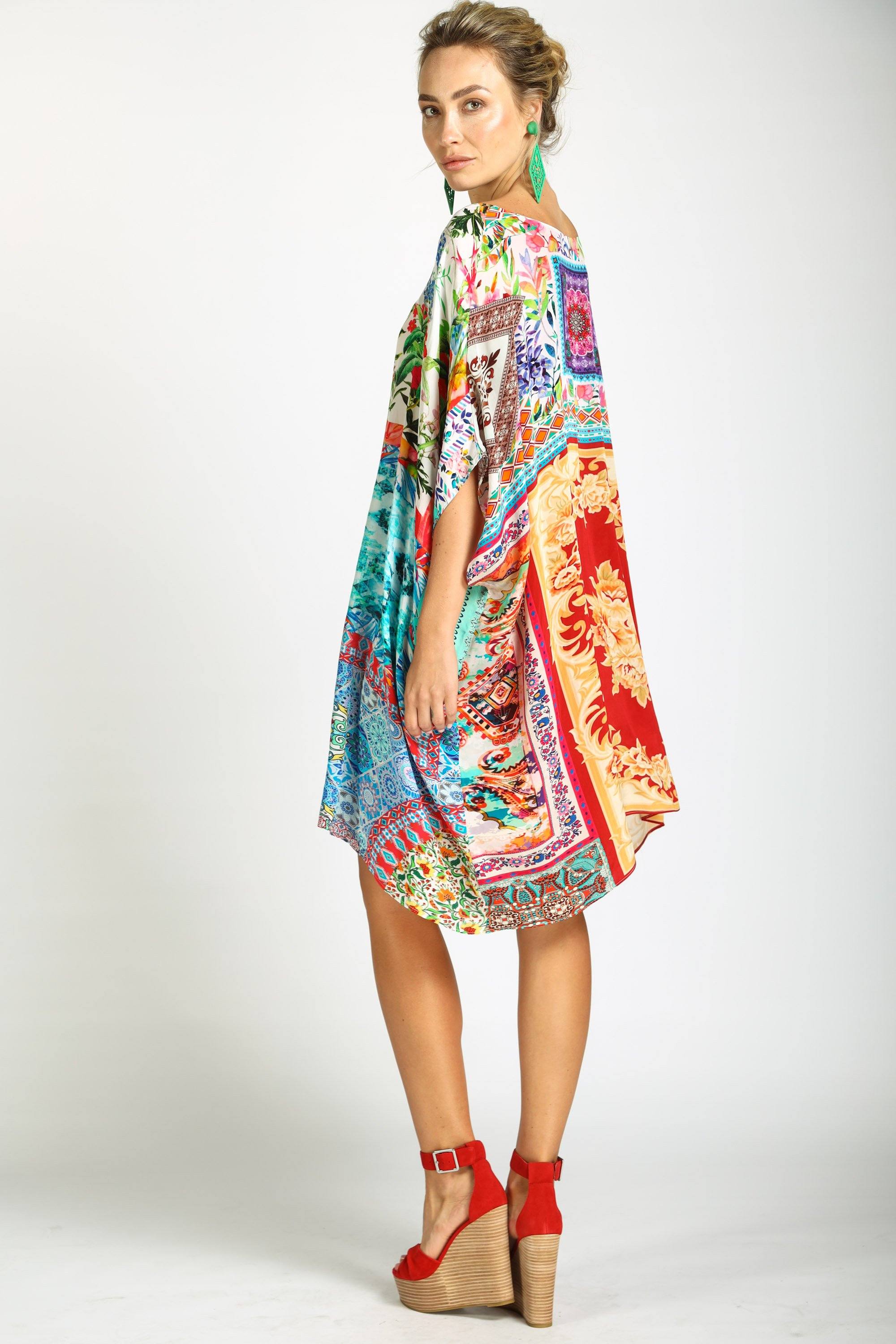 Side view of the Damascus Short Box Kaftan from Bondi (TheSwankStore). This vibrant kaftan dress showcases a rich, multifaceted patchwork design with one long, flowing sleeve and an exposed shoulder, ending above the knee.