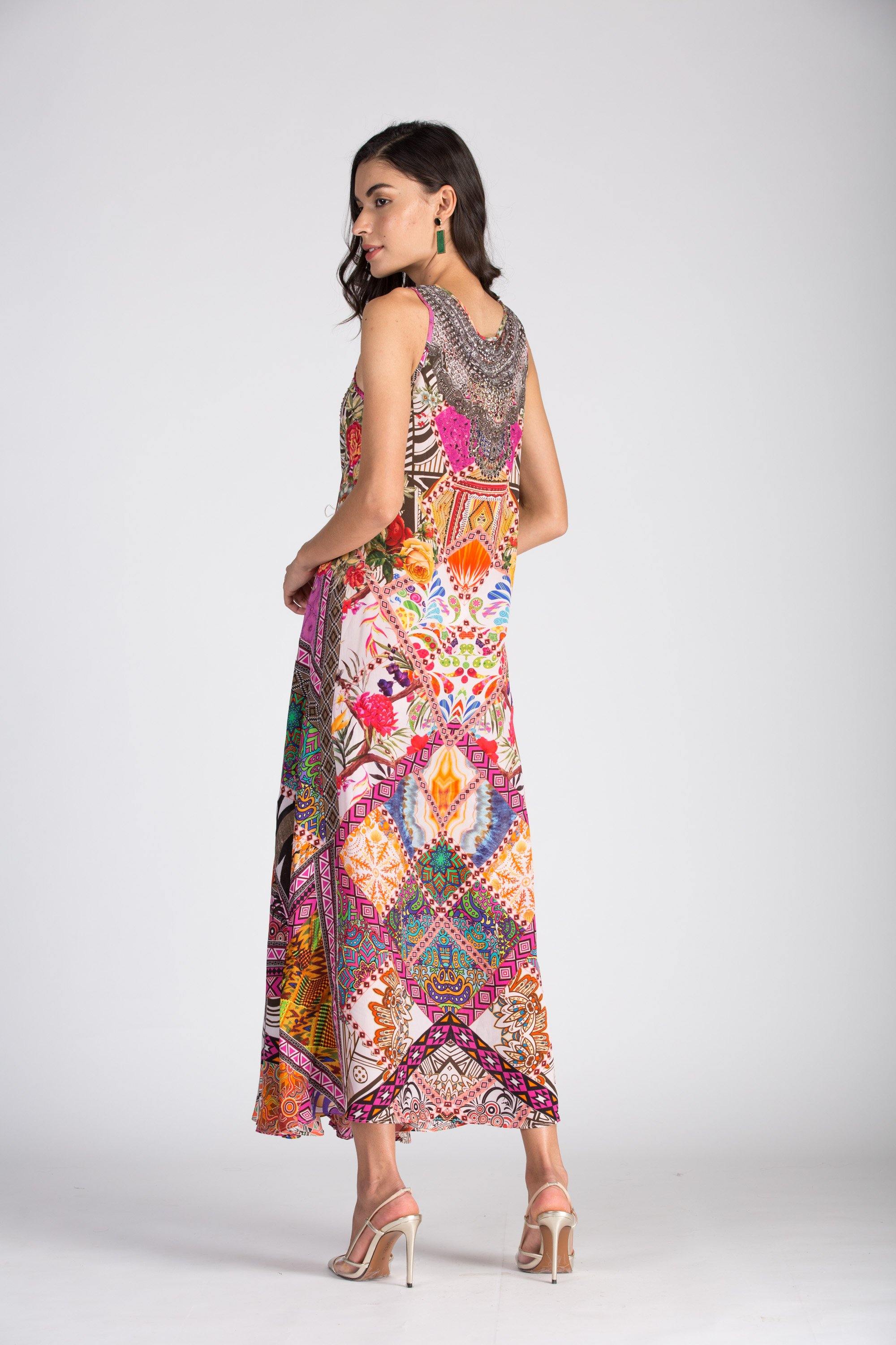 Bondi Tunisia Sleeveless Maxi Kaftan Dress with a subtle V-neckline. The dress has a mixed pattern of detailed bohemian prints and a handkerchief hem that flares out at the ankle.