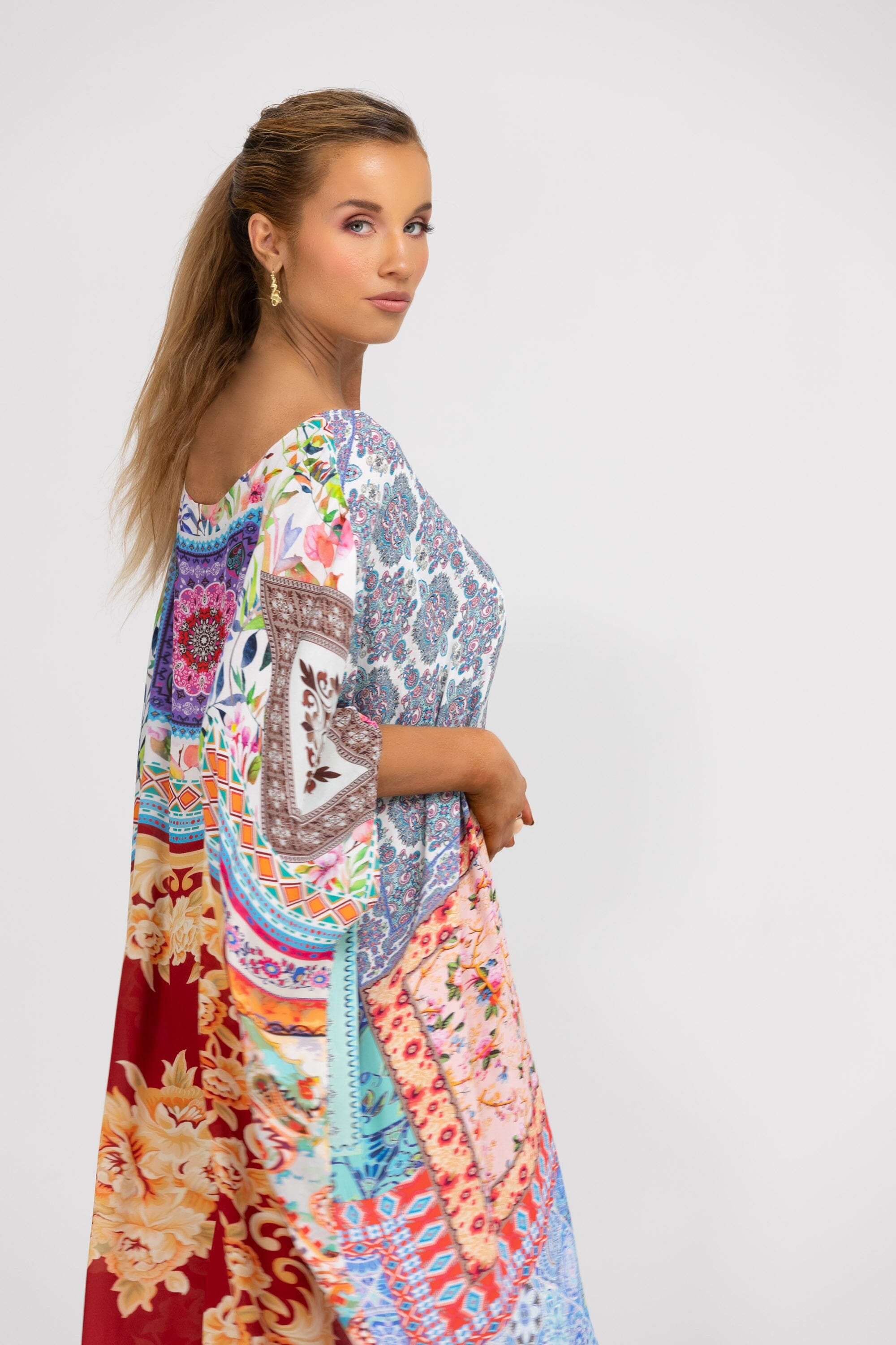 Side View A short kaftan dress, named Damascus, with a boxed, flowing silhouette. The patchwork pattern is composed of various mixed prints, designed for a relaxed fit. Available at Bondi / TheSwankStore.
