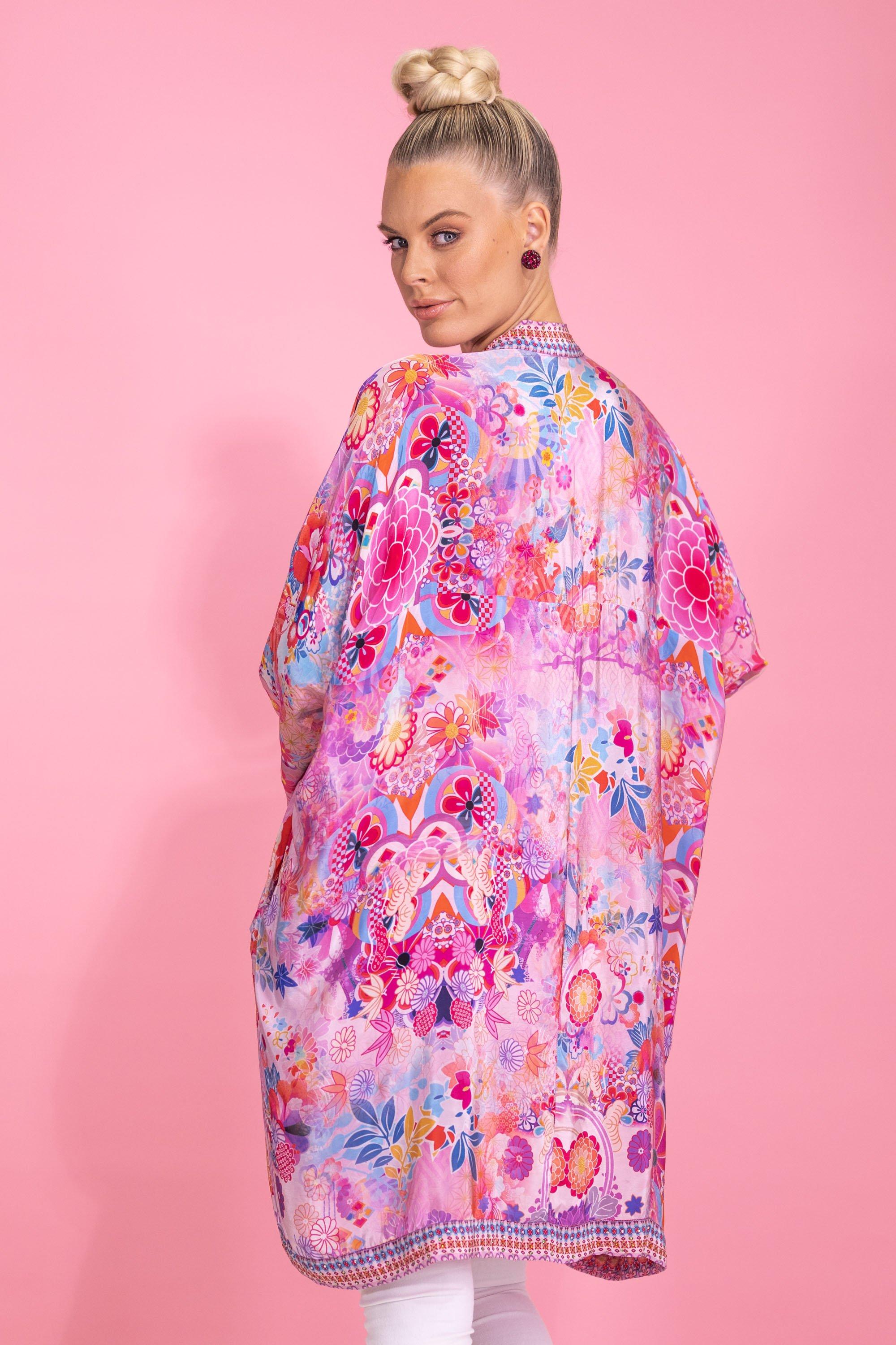 Back view of the Bondi (TheSwankStore) floral kimono cardigan. The long, flowing kimono features an intricate, all-over vibrant pink, orange, and purple floral and leaf print, highlighting the full drape of the garment.