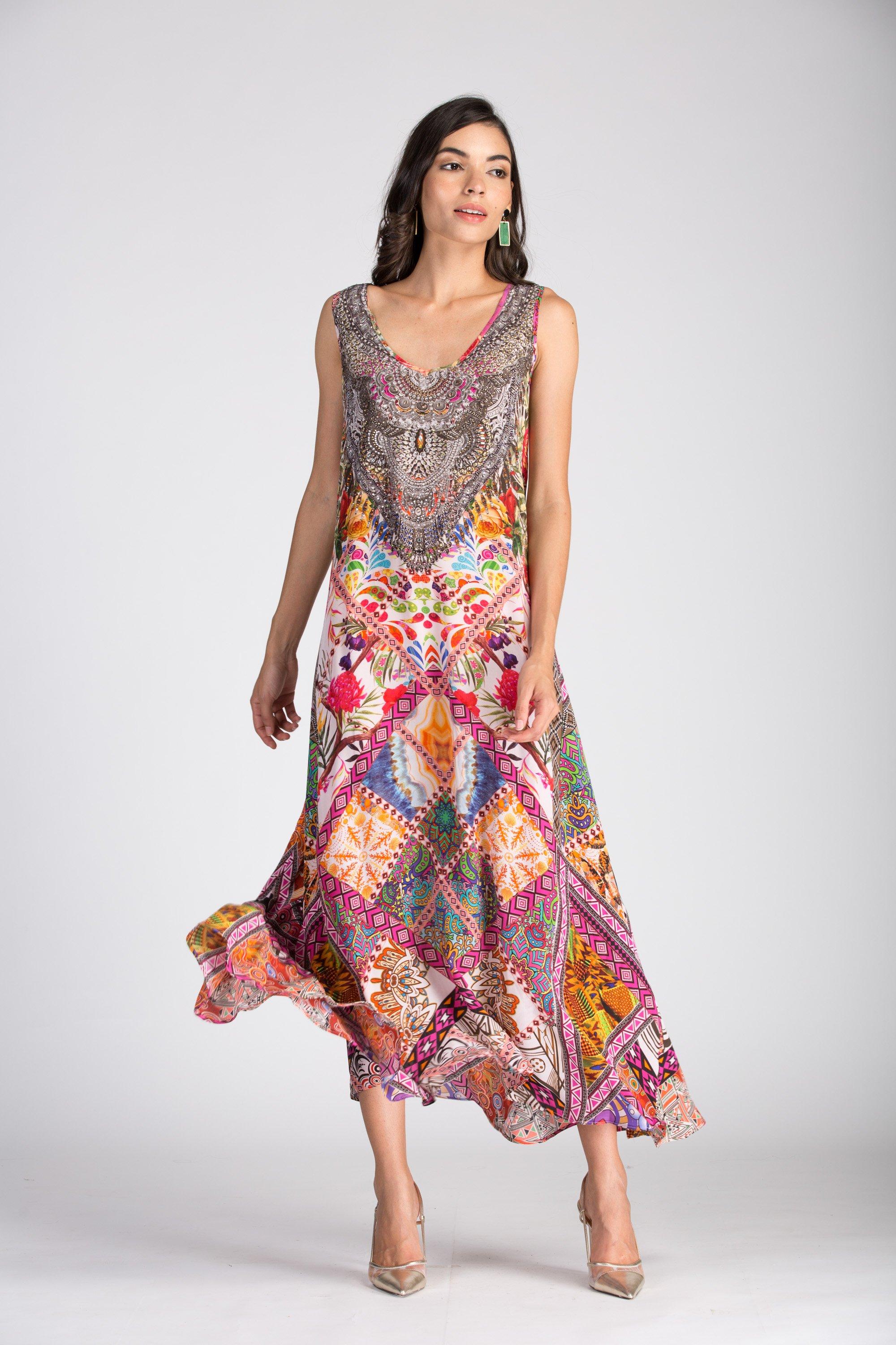TUNISIA - SLEEVELESS MAXI DRESS by Bondi (formerly TheSwankStore). Full-length photo of a woman wearing a flowing maxi dress with a colorful, complex, symmetrical patchwork and paisley print, featuring a subtle v-neck and vibrant pink, orange, and purple hues.