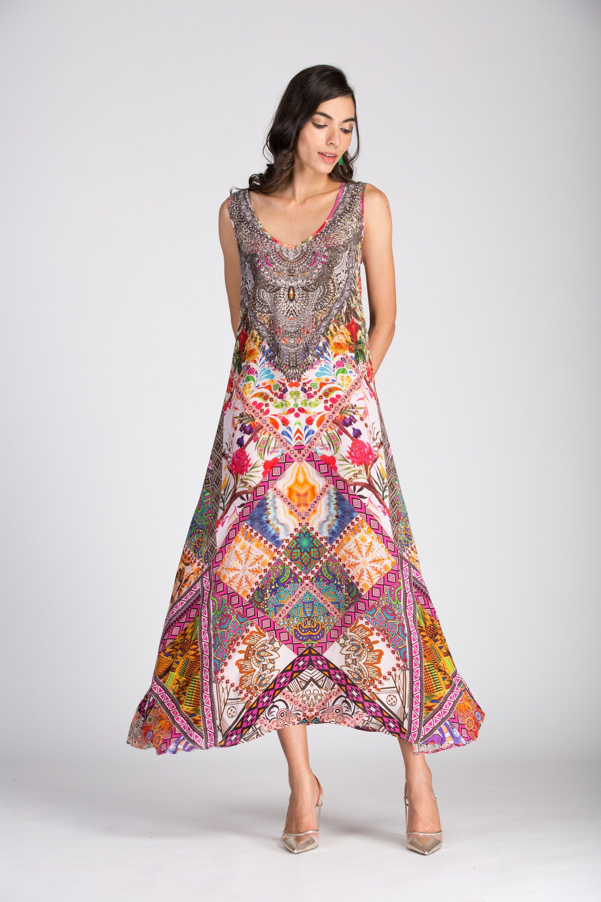 Full-length image of the Tunisia Sleeveless Maxi Dress by Bondi (TheSwankStore) on a model against a white background. The dress features a fluid, full skirt and an intricate print in warm colors.